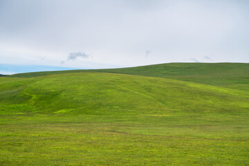 Grassland and mountains in a cloudy day. Photo in Kalajun grassland in Xinjiang, China.