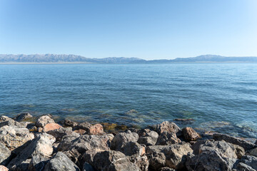 Fototapeta na wymiar The calm surface of the lake and rocks. Shot in Sayram Lake in Xinjiang, China.