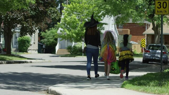 Girls out trick or treating on halloween from behind in neighbourhood