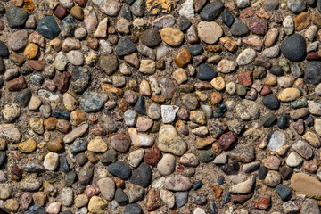 Top view close-up texture background of a vintage exposed aggregate stone patio surface in bright...