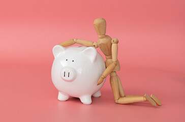 finance saving money, withe piggy bank on pink background and wooden mannequin 