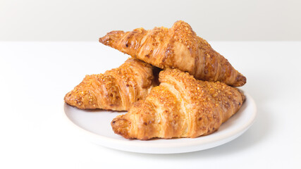 White Plate with three tasty croissants on white background. French food