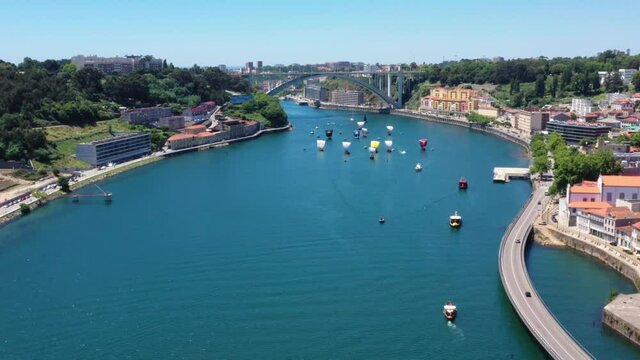 Aerial view tracking many rabelo cargo ships cruising on Douro River in Oporto during summer. High angle wide shot