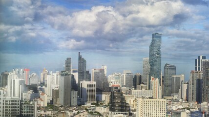 a beautiful cityscape of high buildings in central business district of Bangkok with moving clouds in the background