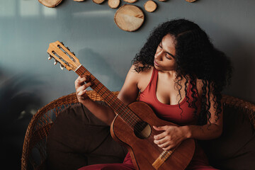 mujer negra de rizos con una guitarra tocando una melodía 