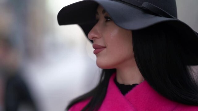 portrait of a brunette in a black hat and a pink coat. close-up