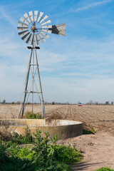 Old water mill in the middle of a field while it is being planted. Pool to give water to the animals