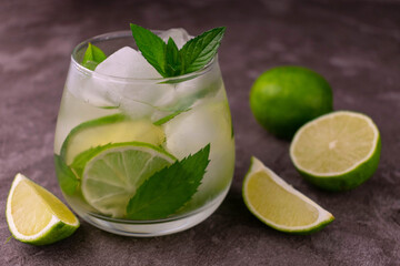 Ice green tea with lime and mint in a glass on a gray background.