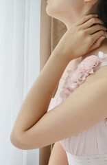 Woman in pink formal dress and holding her neck 