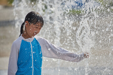 Fototapeta premium 真夏の公園の水エリアで遊んでいる可愛い女の子の様子