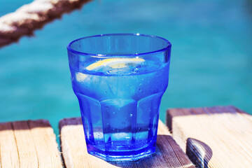 Glass with Water and Lemon Slice on a Sea Background