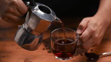 Fototapeta na wymiar Barista pouring coffee from moka pot into a cup.