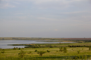 The calm wide river carries its waters under the morning sky. Landscape with hills, trees and a river in Russia