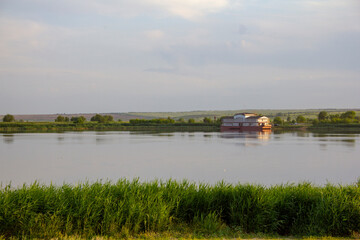 Fototapeta premium A serene rural landscape in the hinterland. Calm river at dawn, pier, landing stage waiting for the ship.