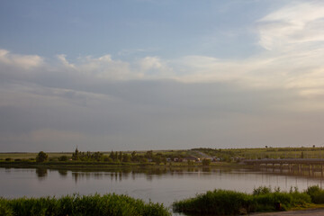 Car trip to the South. Early morning on the bank of a calm river. Cars are driving across the bridge.