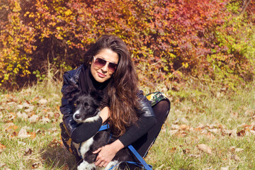 Fototapeta na wymiar Beautiful Young Woman Hugging her Adopted Dog in the Autumn Park 