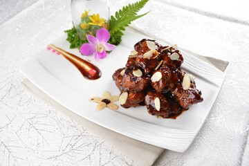 Stir fried dark plum sweet and coffee sauce pork spare ribs meat with almond in white background asian banquet menu