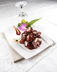 Stir fried dark plum sweet and coffee sauce pork spare ribs meat with almond in white background asian banquet menu
