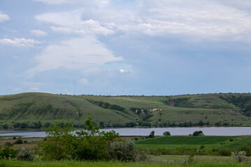 Fototapeta premium The calm wide river carries its waters under the morning sky. Landscape with hills, trees and a river in Russia