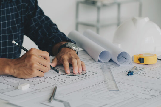 Close-up Of Engineer Hand Drawing Plan On Blue Print with architect equipment and architectural plan at a table in a modern office. sketching a construction project, and workflow construction concept