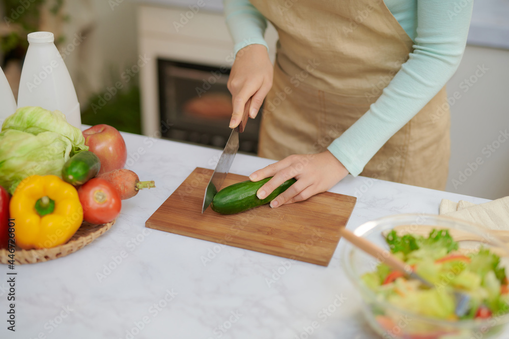 Wall mural young woman with blender chopping green vegetables for detox shake at home