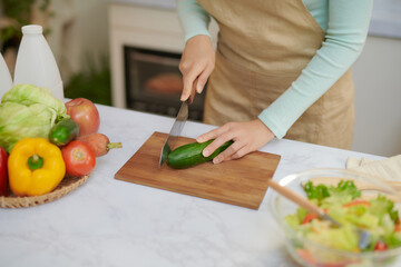 young woman with blender chopping green vegetables for detox shake at home
