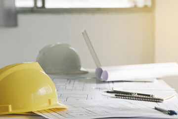yellow hard safety wear helmet hat placed on blueprint at construction site-building.helmet for workman as engineer or worker. concept safety first