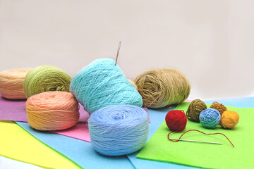 skeins of thread and a needle scattered on multi-colored foamiran paper, multi-colored skeins of thread