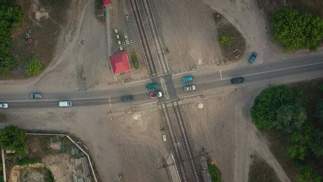 Cars cross rails at an automatic level crossing, aerial top view.