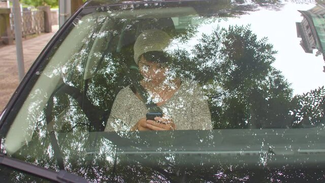 A woman passenger is sitting in the cabin of a car, she is using a smartphone. Using the mobile application search for a sober driver.