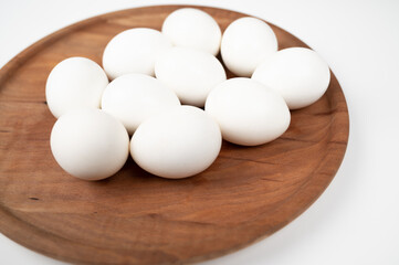 White eggs in a wooden plate isolated on a white background. Organic eggs.