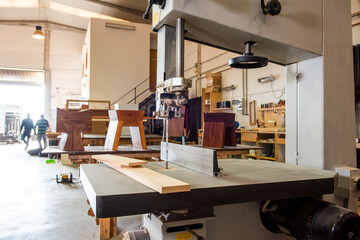 view of the interior of a carpentry workshop with two operators in the background blurred and a...