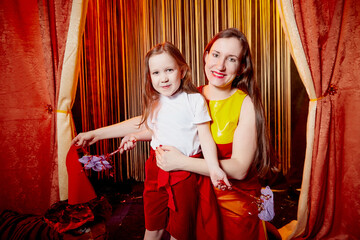 Family during a stylized theatrical circus photo shoot in a beautiful red location. Models mother...
