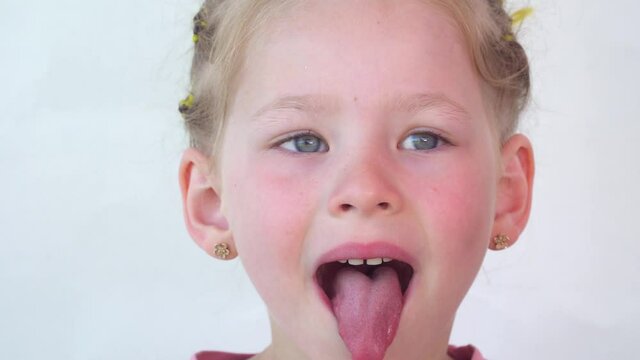 Cheerful child. Girl laughs close-up of the face on a white background. little girl show tongue, throat. portrait with wide open mouth and protruding tongue. with clear view pulls out long tongue. 