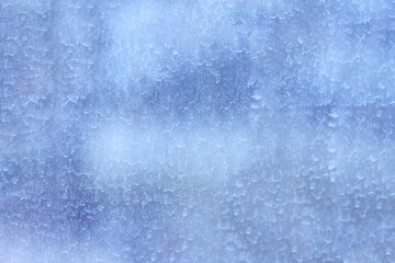 The surface of the dirty window glass, covered with dusty traces of raindrops. Blue blurred abstract texture.