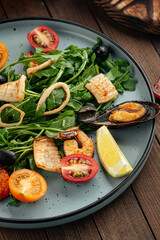 Plate of gourmet seafood salad with greens on a wooden background