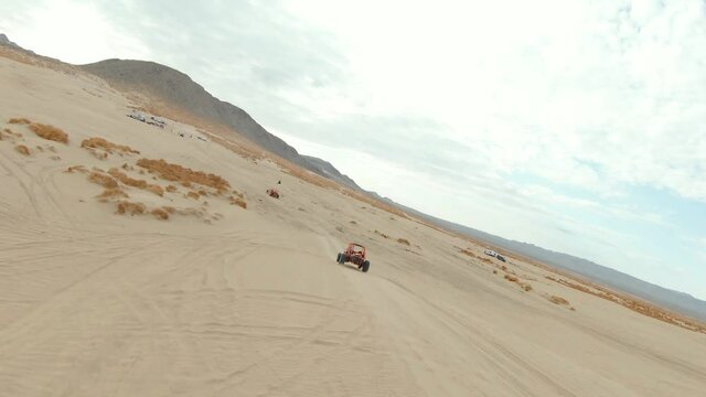 Orange Dune Buggy Driving in the Desert Sand Dunes
