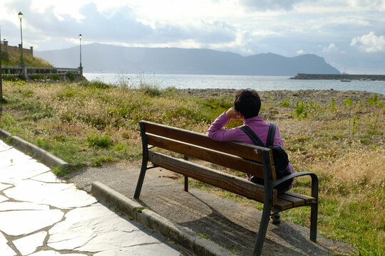 Female sitting on a bench and looking at the horizon in Espasante, La Coruna, Spain