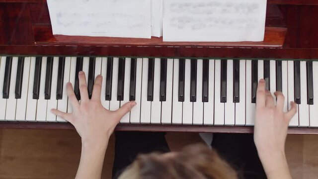 Professional pianist performs classical piece notes on piano, top view, closeup. Student plays notes on piano with two hands