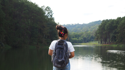 Young Asian woman traveler backpack standing among forest mountain and the lake in beautiful natural