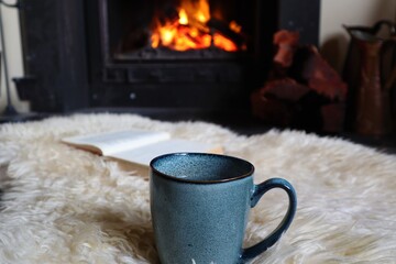 Mug of tea and book, read in front of cozy fireplace in winter