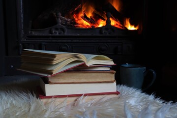 Books and open book in front of open fireplace in winter