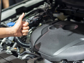 Hand thumb up with the engine of new car