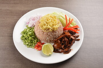 stir fried shrimp paste brown rice with fried meat in dark sauce and vegetable salad main course in wood background asian halal menu