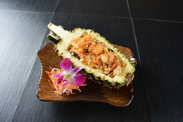 thai pineapple fried rice with seafood and meat in pineapple fruit in black background asian halal menu