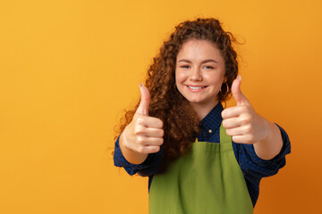 Young woman in a green apron on yellow background