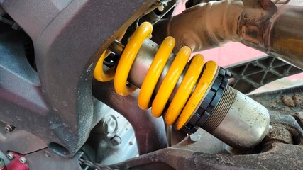 Yellow dirt bike shock absorber. Single spring in the motorcycle's suspension for absorbing and reducing vibration. close-up