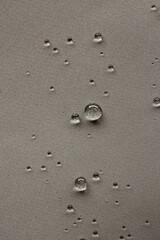 Round water drops on gray textured vertical background.