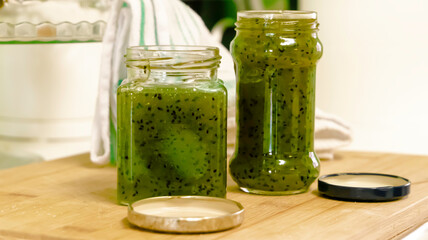 Two jars full of homemade kiwi jam over a wooden surface - selective focus