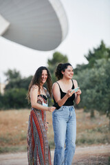 two young women take photos with a giant antenna behind them. They laugh together.
Astronomy. Science. Nature